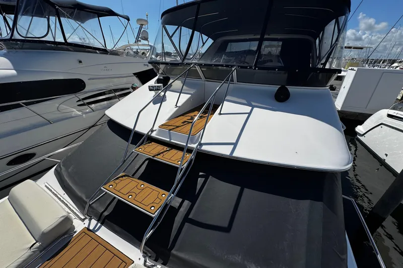 Slide: The Image of 1999 Sea Ray 440 Express Bridge yacht with sleek design and wooden steps at marina. - 13