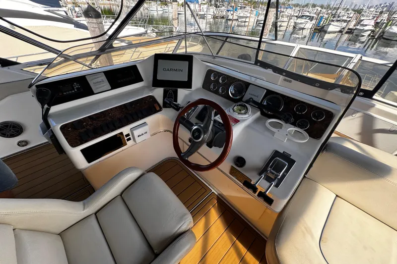 Slide: The Image of 1999 Sea Ray 440 Express Bridge helm with Garmin navigation, wood accents, and marina view. - 19