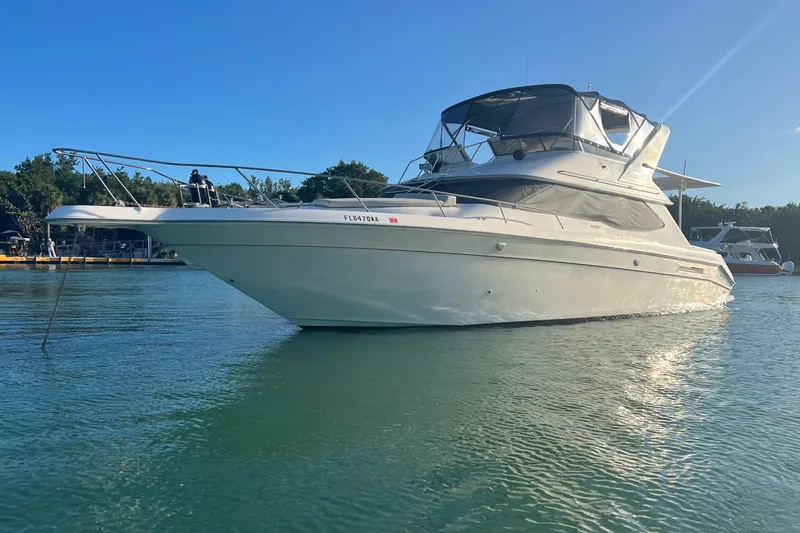 Slide: The Image of 1999 Sea Ray 440 Express Bridge yacht on calm water under clear blue sky. - 2