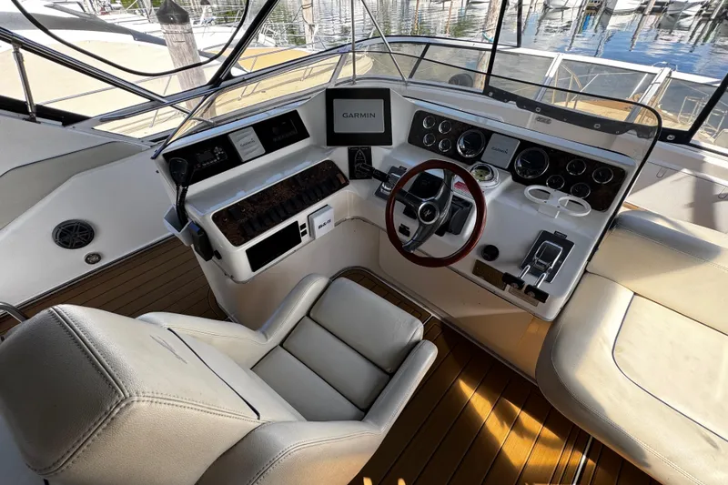 Slide: The Image of 1999 Sea Ray 440 Express Bridge helm with Garmin navigation, leather seating, and wood accents. - 20