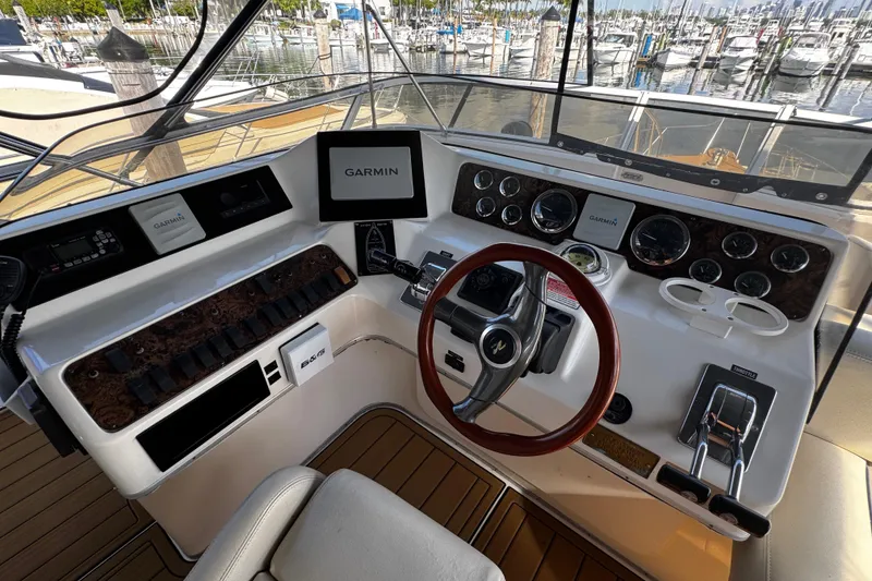 Slide: The Image of 1999 Sea Ray 440 Express Bridge helm with Garmin navigation, wood accents, and marina view. - 21