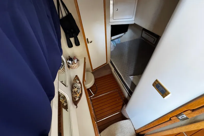 Slide: The Image of 1999 Sea Ray 440 Express Bridge cabin interior with bed, storage, and wooden flooring. - 24