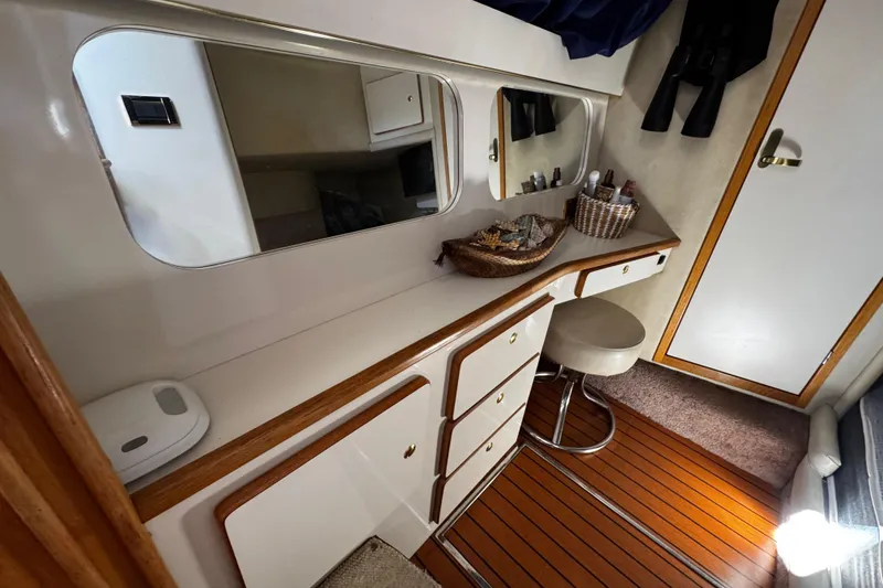 Slide: The Image of 1999 Sea Ray 440 Express Bridge interior with vanity, mirror, and stool. - 25