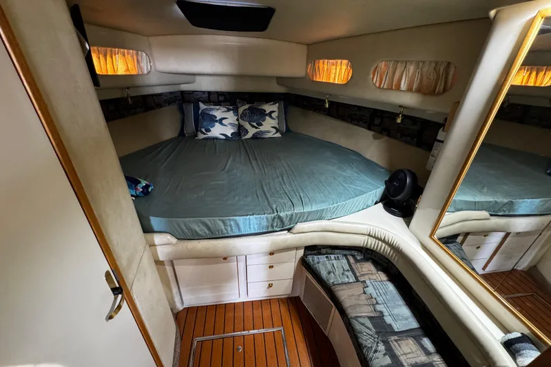 Slide: The Image of 1999 Sea Ray 440 Express Bridge cabin with cozy bed, pillows, and wooden flooring. - 33