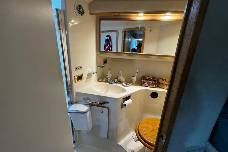 Slide: The Image of 1999 Sea Ray 440 Express Bridge bathroom with sink, mirror, and wooden toilet seat. - 36