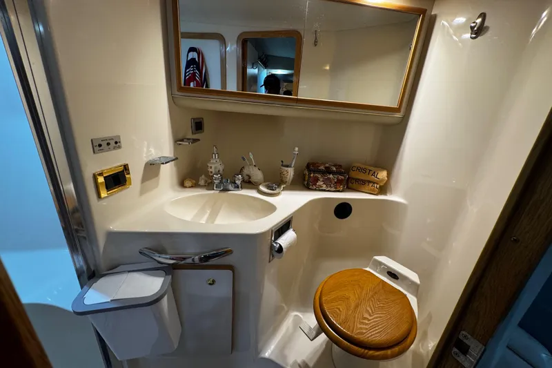 Slide: The Image of 1999 Sea Ray 440 Express Bridge bathroom with sink, mirror, and wooden toilet seat. - 37