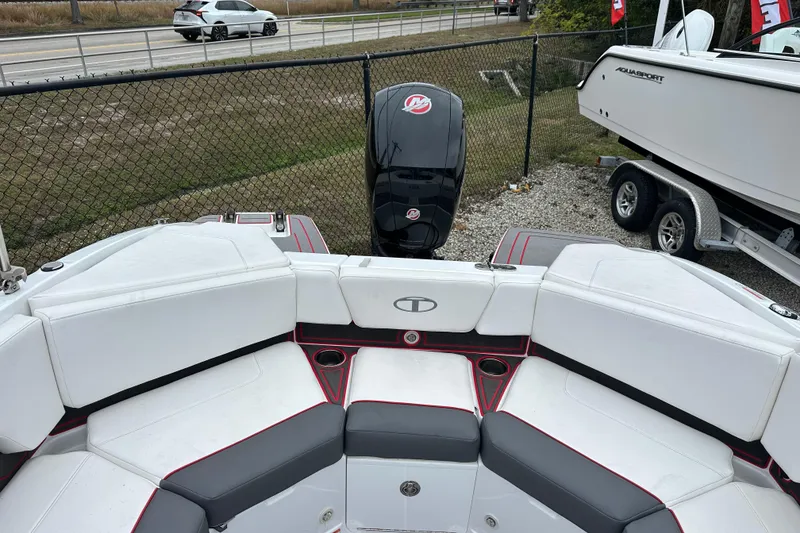 Slide: The Image of 2021 Tahoe 210 S boat interior with white and gray seating, parked near a fence. - 10