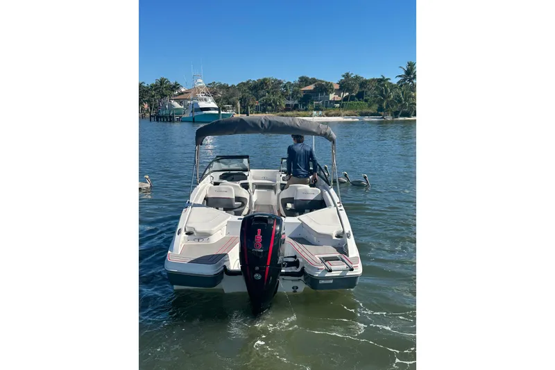 Slide: The Image of 2021 Tahoe 210 S boat on water with canopy, outboard motor, and scenic background. - 2