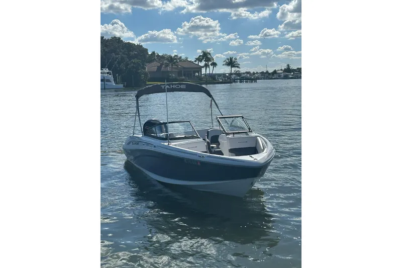 Slide: The Image of 2021 Tahoe 210 S boat on a sunny lake with palm trees in the background. - 3