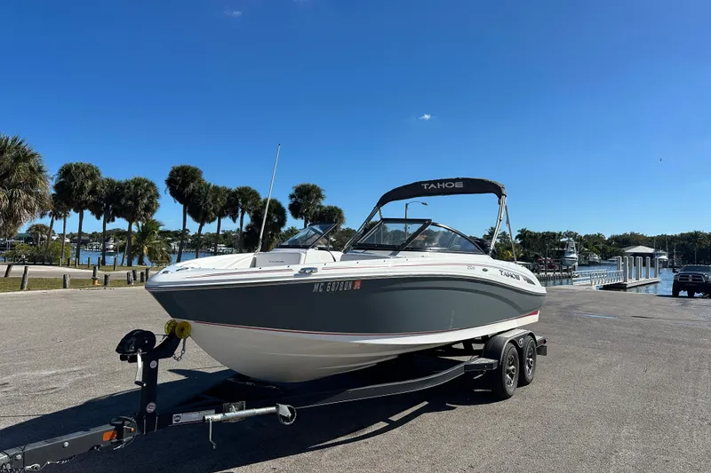 Slide: The Image of 2021 Tahoe 210 S boat on trailer, parked near waterfront with palm trees. - 5