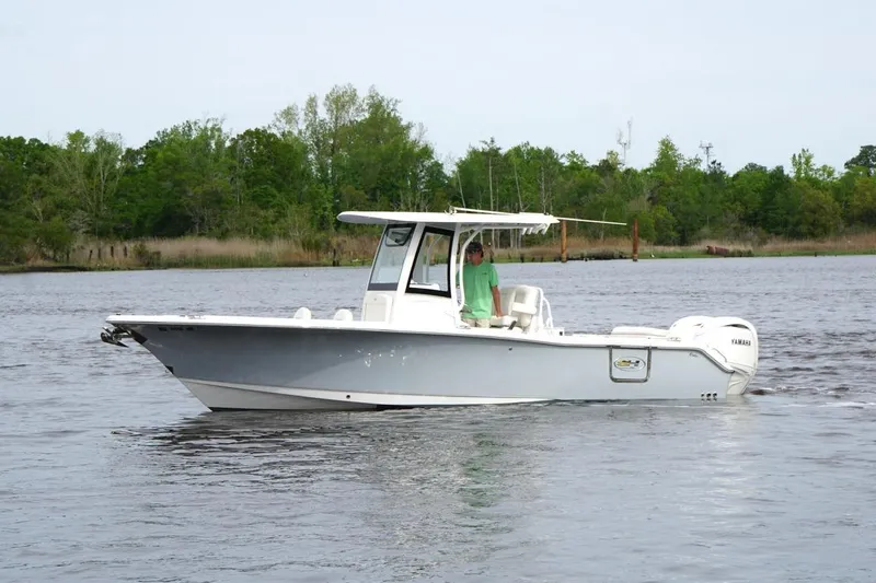 The Image of 2025 Sea Hunt Ultra 265 SE boat cruising on a calm river with lush greenery. - 1