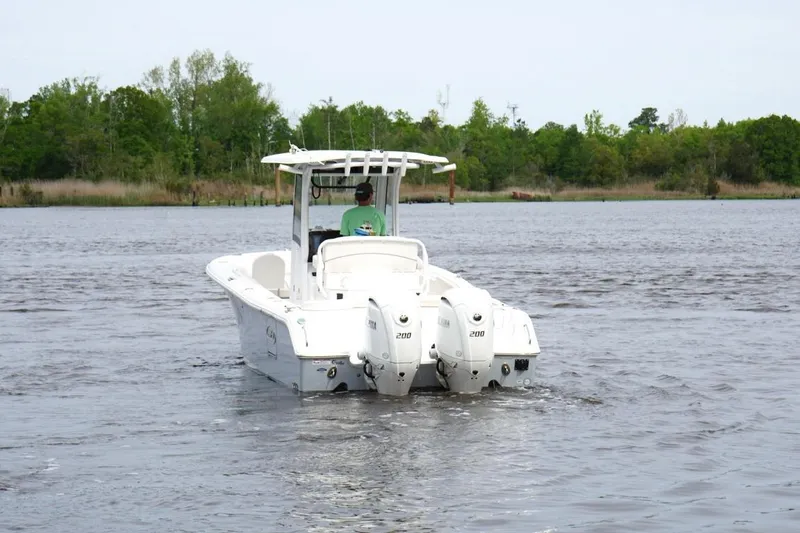 Slide: The Image of 2025 Sea Hunt Ultra 265 SE boat cruising on a calm lake with lush green shoreline. - 4