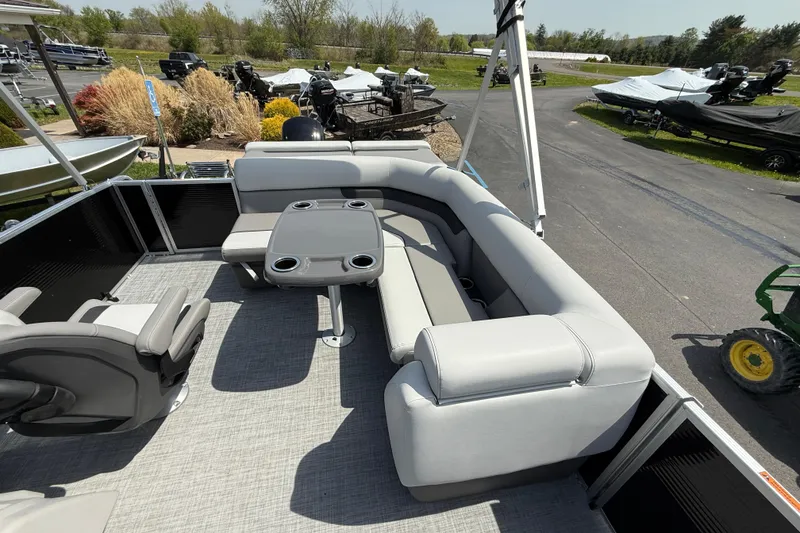 Slide: The Image of 2025 Princecraft Sportfisher 21-2S pontoon boat with gray seating and table, parked outdoors. - 4