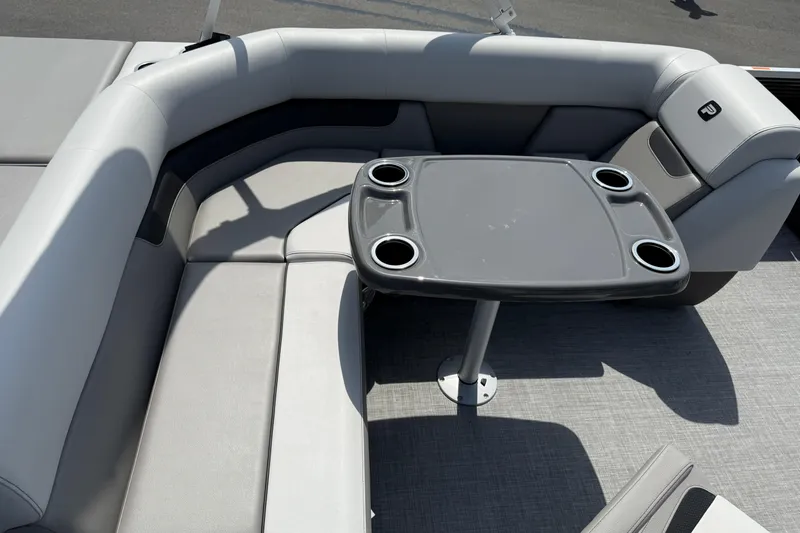 Slide: The Image of 2025 Princecraft Sportfisher 21-2S boat interior with gray seating and table with cup holders. - 6