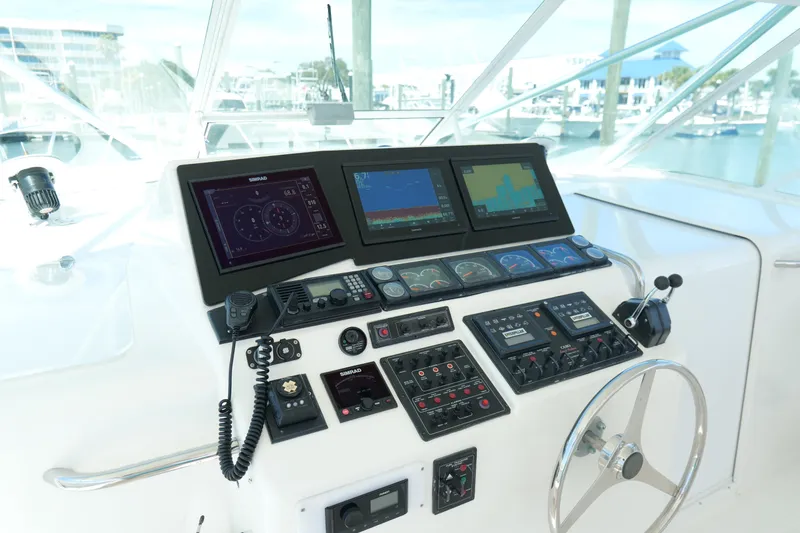 Slide: The Image of Control panel of a 1998 Cabo 45 Express boat with navigation screens and steering wheel. - 13