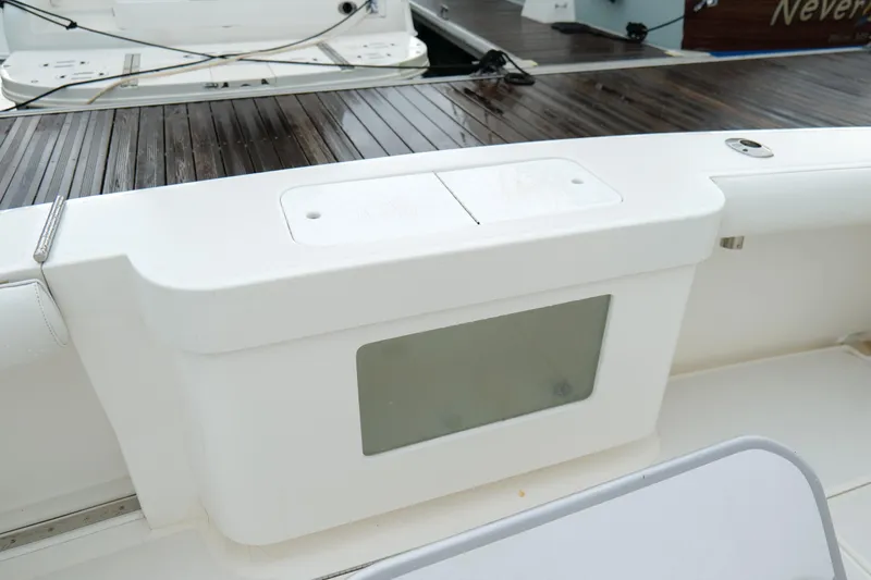 Slide: The Image of 1998 Cabo 45 Express boat deck with white storage compartment and wooden flooring. - 44