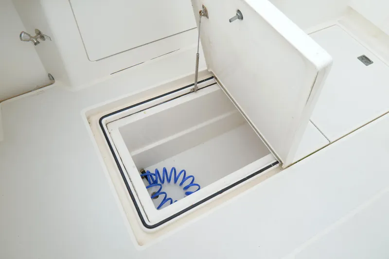 Slide: The Image of Open storage compartment on 1998 Cabo 45 Express boat with blue coiled hose inside. - 46