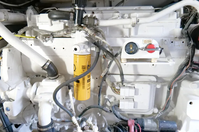 Slide: The Image of Engine compartment of a 1998 Cabo 45 Express boat, featuring hoses and a yellow filter. - 52