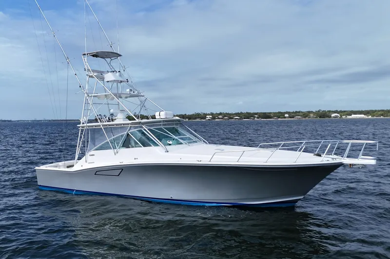 Slide: The Image of 1998 Cabo 45 Express yacht on open water under a cloudy sky. - 7