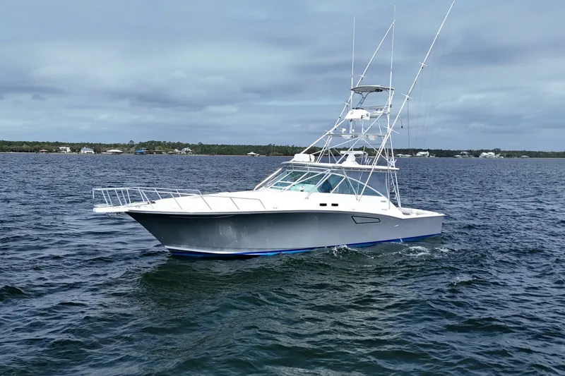 Slide: The Image of 1998 Cabo 45 Express yacht cruising on open water under cloudy skies. - 9