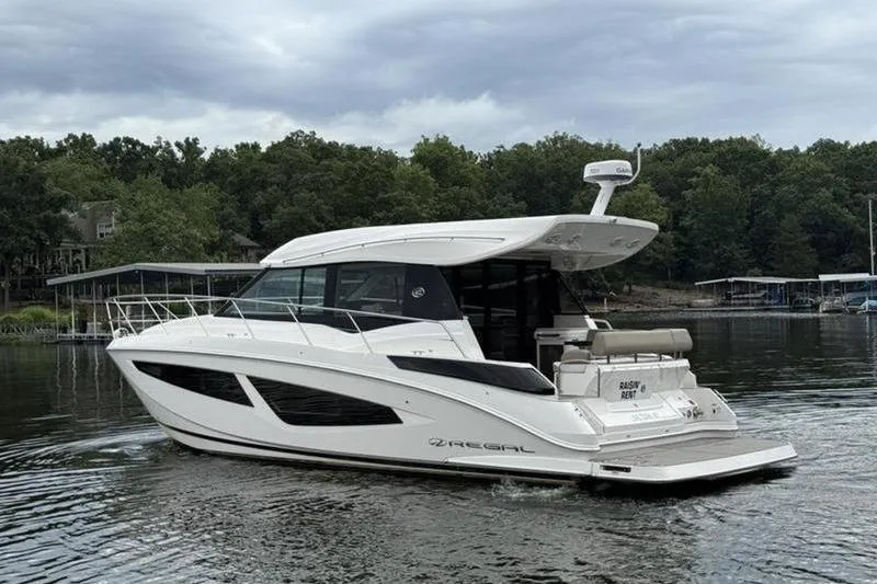 Slide: The Image of 2017 Regal 42 Grande Coupe yacht on a serene lake with lush greenery. - 10