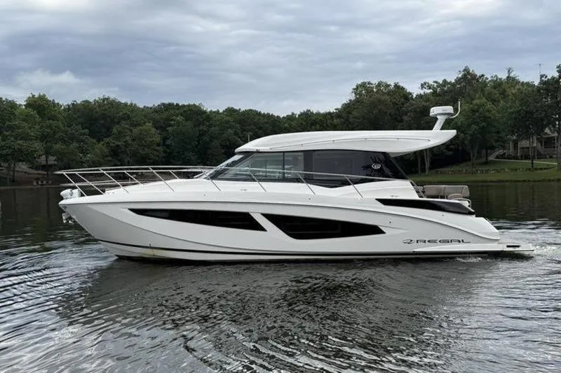 Slide: The Image of 2017 Regal 42 Grande Coupe yacht cruising on a serene lake under cloudy skies. - 2