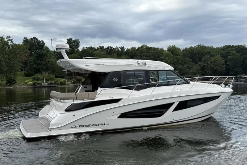 Slide: The Image of 2017 Regal 42 Grande Coupe yacht cruising on a serene lake with lush greenery. - 3