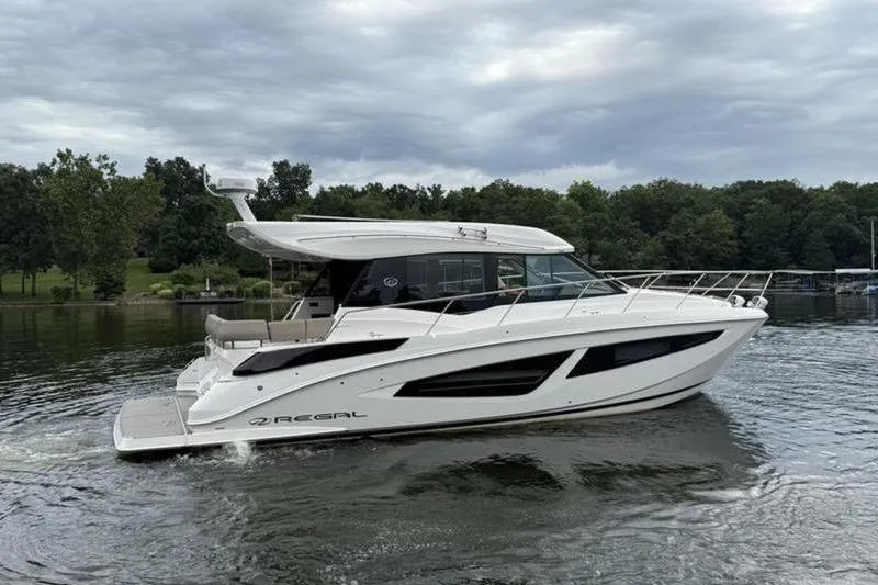 Slide: The Image of 2017 Regal 42 Grande Coupe yacht cruising on a serene lake under cloudy skies. - 5