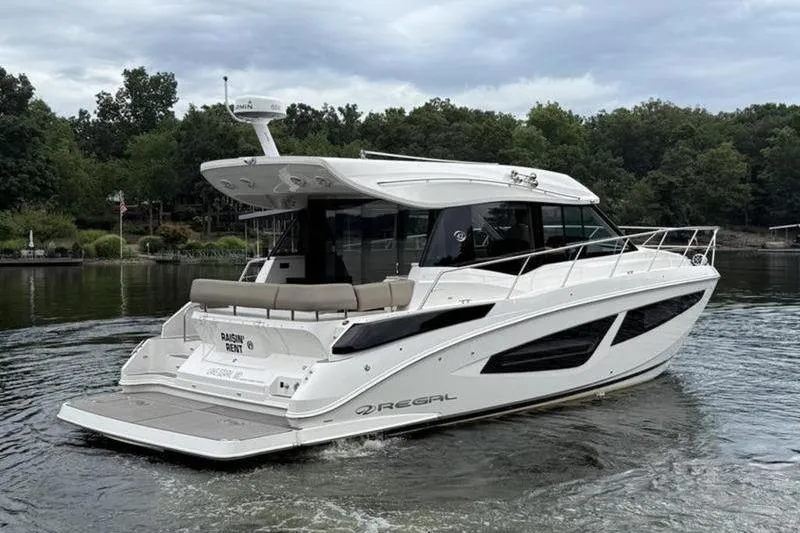 Slide: The Image of 2017 Regal 42 Grande Coupe yacht cruising on a serene lake with lush greenery. - 8