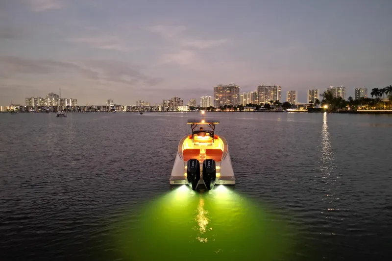 Slide: The Image of Lilybaeum Lipari 31 boat illuminated on water at dusk, city skyline in background, 2026 model. - 35