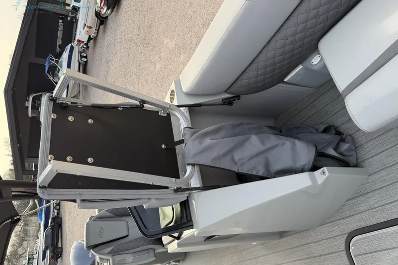 Slide: The Image of 2022 Manitou 27 LX SRW boat interior with seating and storage compartment. - 7