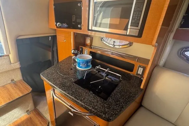 Slide: The Image of 2011 Chaparral 270 Signature boat interior with kitchenette, featuring microwave and granite countertop. - 15