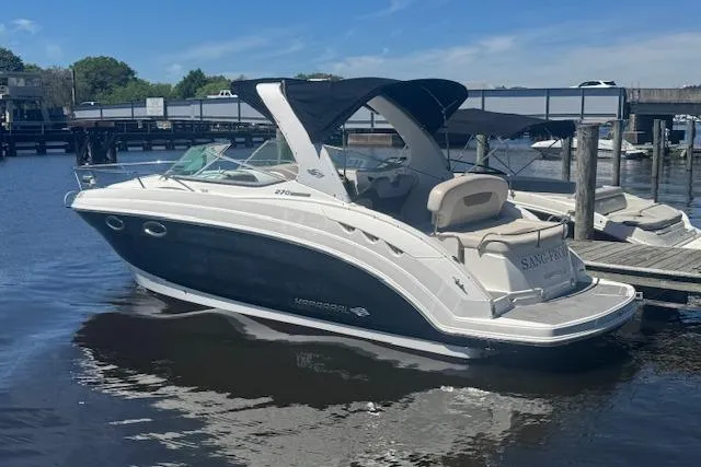 Slide: The Image of 2011 Chaparral 270 Signature boat docked at marina, featuring sleek design and black canopy. - 2