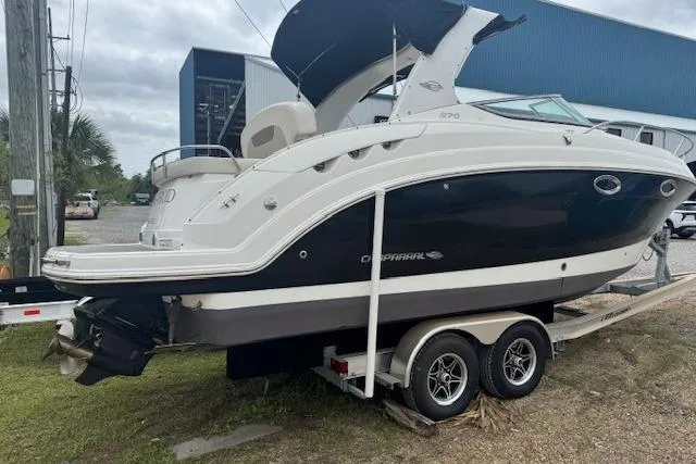 Slide: The Image of 2011 Chaparral 270 Signature boat on trailer, parked outdoors near a blue building. - 21