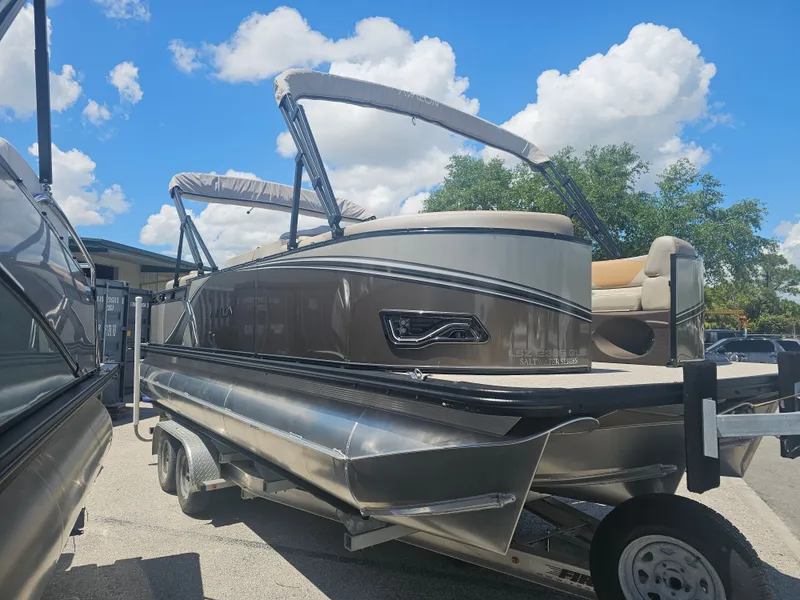 Slide: The Image of 2026 Avalon LSZ 2385 Quad Lounger Tritoon on trailer, blue sky. - 2