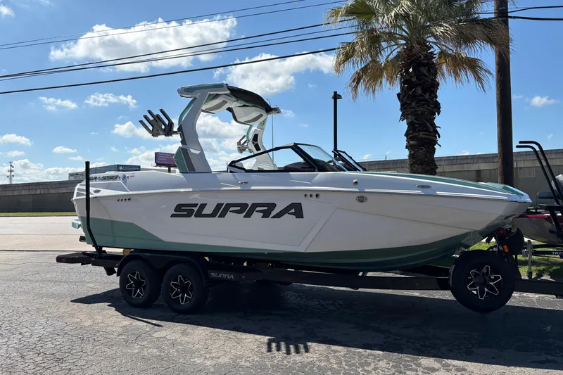 The Image of 2026 Supra SA 550 boat on trailer under clear sky, parked near palm tree. - 1
