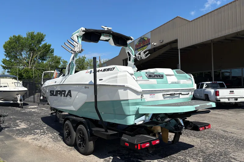 Slide: The Image of 2026 Supra SA 550 boat on trailer, parked outside dealership under clear blue sky. - 6