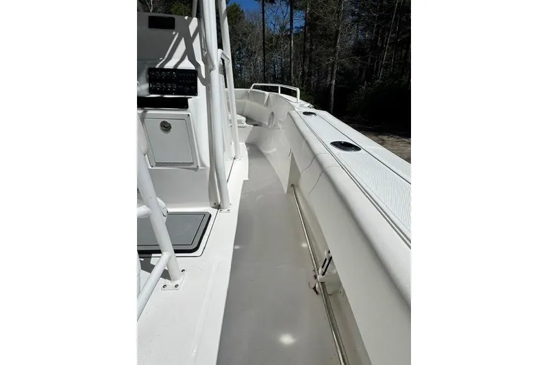 Slide: The Image of 2021 Edgewater 208CC boat interior with white deck and console, surrounded by trees. - 10
