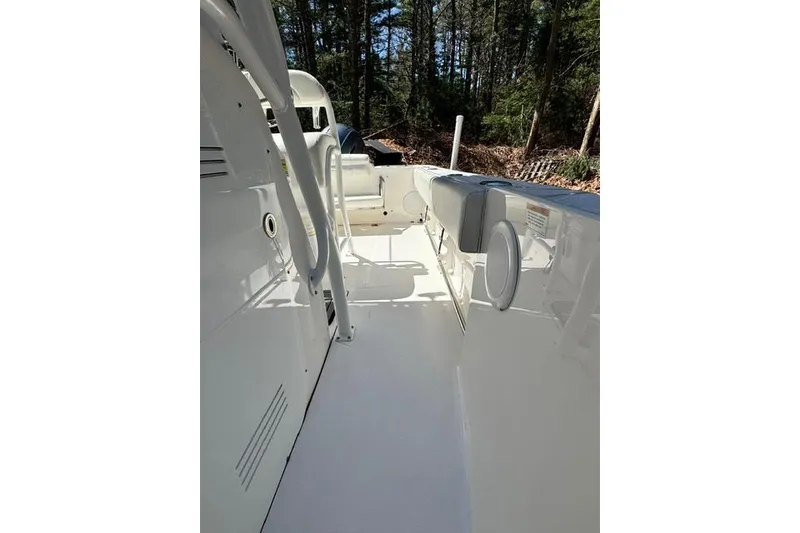 Slide: The Image of 2021 Edgewater 208CC boat interior with white deck and seating, surrounded by trees. - 12