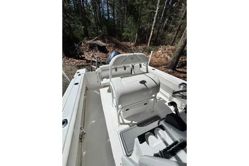 Slide: The Image of 2021 Edgewater 208CC boat interior with seating, set in a wooded area. - 14