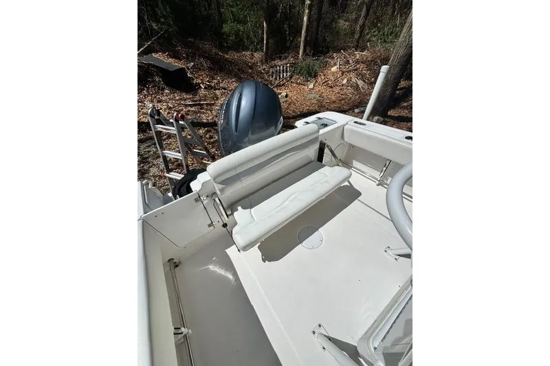 Slide: The Image of 2021 Edgewater 208CC boat interior with seating and outboard motor in wooded area. - 15