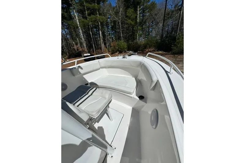 Slide: The Image of 2021 Edgewater 208CC boat interior with white seating and forest background. - 18