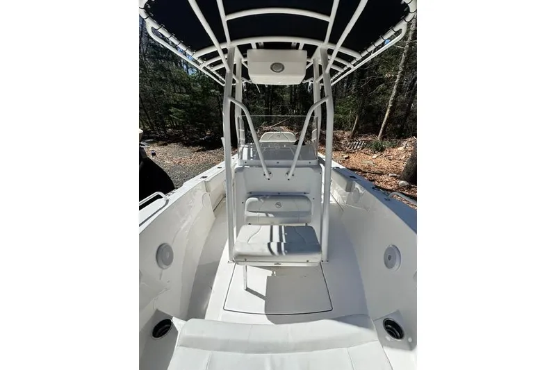 Slide: The Image of 2021 Edgewater 208CC boat interior with seating and canopy, surrounded by trees. - 20