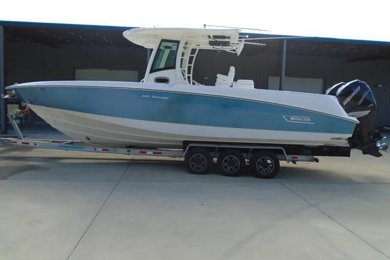 Slide: The Image of 2011 Boston Whaler 330 Outrage boat on trailer, side view, blue and white design. - 2