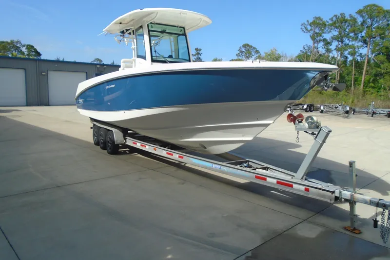 Slide: The Image of 2011 Boston Whaler 330 Outrage boat on trailer, parked outdoors. - 4