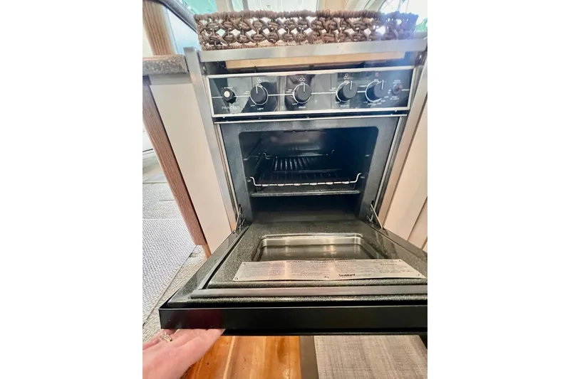 Slide: The Image of 1999 Maxum 4100 SCB yacht kitchen oven with open door and control knobs. - 13
