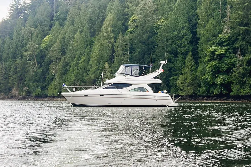 Slide: The Image of 1999 Maxum 4100 SCB yacht cruising on a forest-lined waterway. - 2