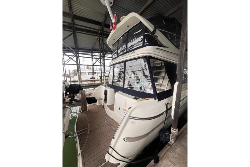 Slide: The Image of 1999 Maxum 4100 SCB yacht docked in a covered marina, showcasing sleek design and spacious deck. - 28