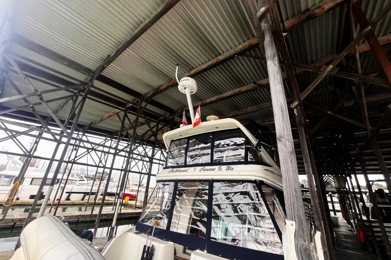 Slide: The Image of 1999 Maxum 4100 SCB yacht docked under a metal canopy at a marina. - 29