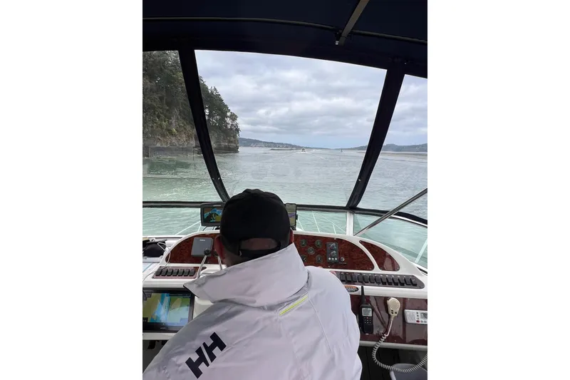 Slide: The Image of Person steering 1999 Maxum 4100 SCB boat on scenic waterway, surrounded by lush landscape. - 45